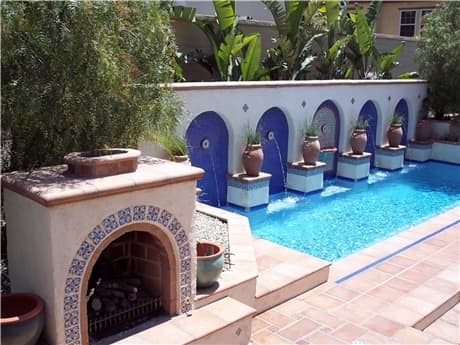 four arches blue tile walls accent the large water fountain with a tiled fireplace in the foreground