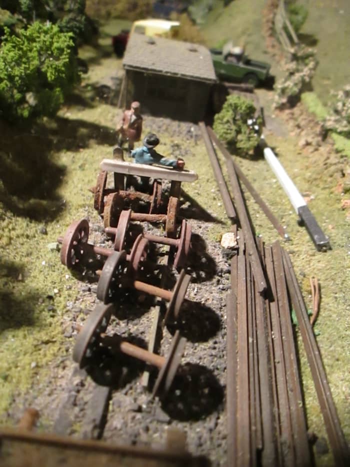 Assorted lineside detritus, plastic axles and wheels painted to resemble rusted steel. At the back is a pair of Ratio sheds fixed together, painted and weathered to look like creosoted timber