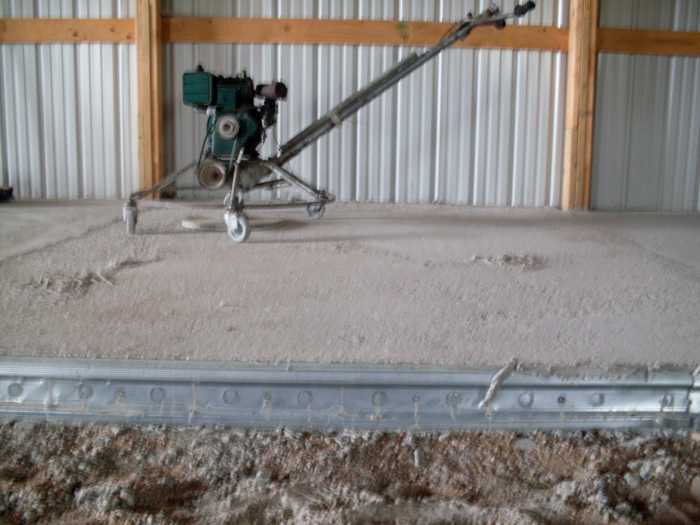 A machine to smooth the leveled underlayment for the concrete pad sits off to the side, on a section which has already been done.