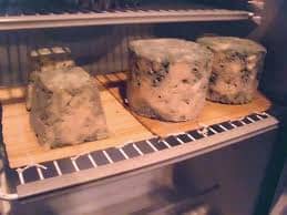 Place the pierced cheese on a flat plate or rack that has been topped with a cheese mat. Place the cheese in a cool room or refrigerator. The cheese pictured here shows some maturity and age and is in a variety of shapes and pounds.