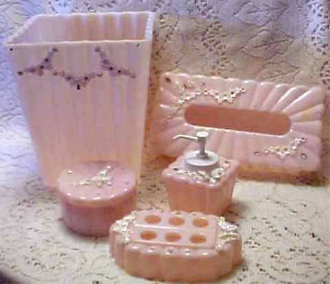 pink bathroom accessories such as toothbrush holder, tissue box, water, perfume and wastebasket