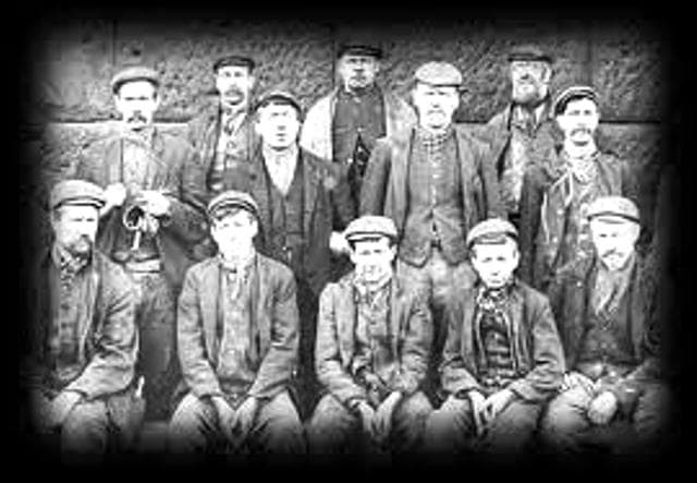 A group photograph taken at Pit Top (Upsall) in front of the steam winder that operated the cage used by the miners to descend into the pit to go to work