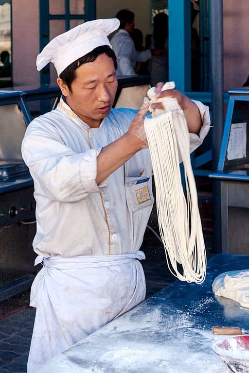 Skilled cook produces long strands of noodles in record time.