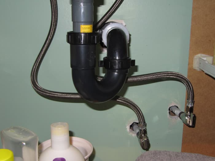 This picture is of under a bathroom sink showing the shut off valves and the flexible water supply lines going up to the taps.