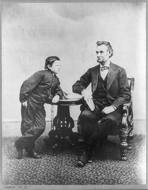 [Abraham Lincoln, seated and holding a book, with his son Tad (Thomas) leaning on a table.