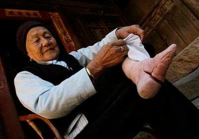 FOOT BINDING was officially ended after the Communists took power in 1949. The foot was broken across the arch and 4 toes wrapped under the foot. The smallest feet were the "best" and these women had to be carried, unable to walk.