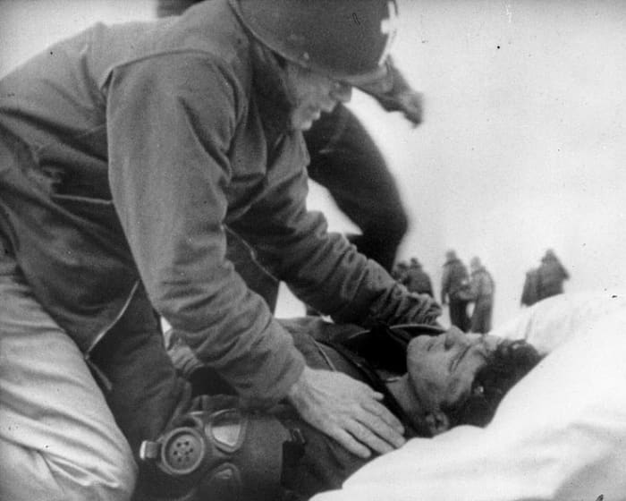 Lieutenant Commander Joseph T. O'Callahan, USNR gives "Last Rites" to an injured crewman aboard USS Franklin, 19 March 1945. The crewman is reportedly Robert C. Blanchard, who survived his injuries.