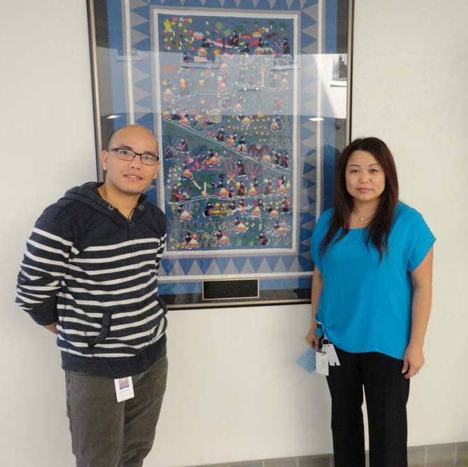 Eldrick Chang and Say Xiong in front of the story quilt at the Fresno Adult Community Education center.