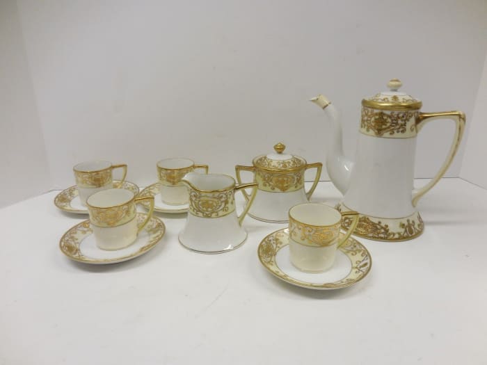 NORITAKE CHRISTMAS BALL 13 PIECE DEMITASSE SET. The coffee pot stands 6.5" high and 6.5" wide with some gold loss on the handle. The creamer is 2.5" high and 3" wide. The sugar bowl is 3.5" high and 4" wide. The saucers are 4" in diameter and the