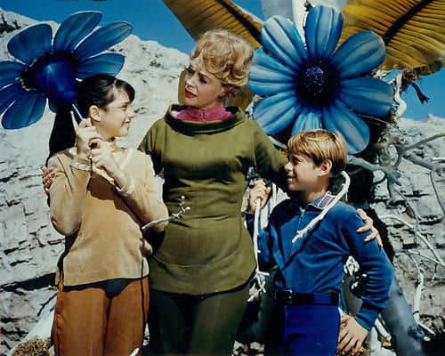 Penny Robinson, Maureen Robinson and Will with some very large flowers on a distant world made by the imagination of Irwin Allen..