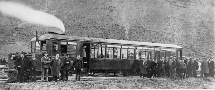 In Lincolnshire, Clayton steam railcar rests along its route wiyth passengers, crew and railway personnel at the trackside
