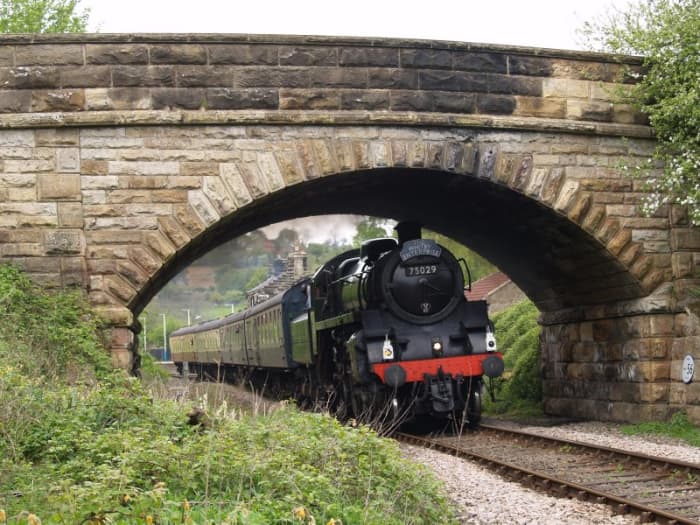 Preserved BR Class 4 4-6-0 75029 brings the 'Whitby Enterprise' through Danby Station under the road bridge