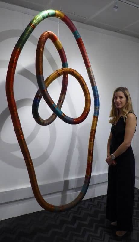 Curator Claudia Trosso stands beside Inka Space, a mobile structure made with copper and thread.
