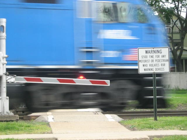 Pedestrian crosswalk near Downtown Hinsdale with the gate down, lights flashing, and a warning to not cross when trains are approaching