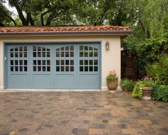 beautiful Mediterranean garage doors with blue paint and arched glass windows and clay tile rool