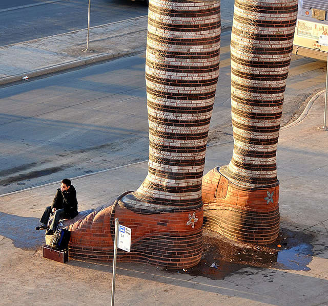 This sculpture is made of bricks and each leg is 20 feet tall. It is located in the middle of Southgate Transit Centre, Alberta (Canada).