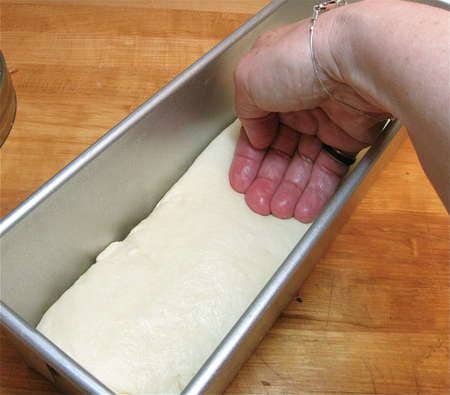 Gently place your punched down bread dough into the loaf pan and shape it a bit, be sure the seam side is on the bottom..