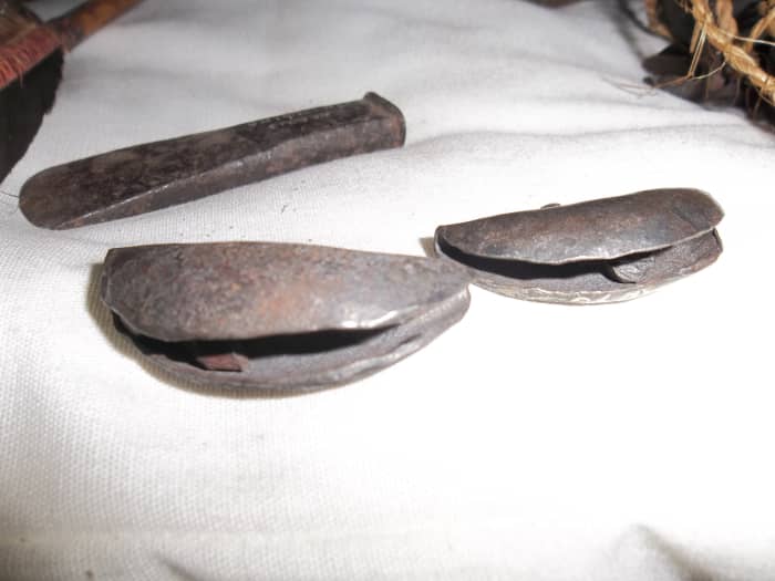 Metal jingles. They were tied with a string to the leg. The leg was stamped rythimically to the music. Ignore the chisel above the jingles.
