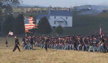 A Living Historian Battalion advances to take its assigned position. The Right Guide is visible in the distance, carrying aloft a marker flag.