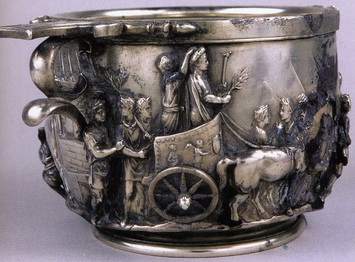 Tiberius in Triumph. Kleiner, A History of Roman Art , p. 105: "The Tiberius cup shows on one side the emperor-to-be riding in a triumphal quadriga holding a laurel branch and an eagle-tipped scepter'