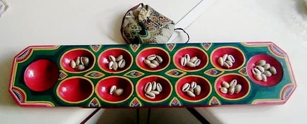 Beautiful mancala game board with cowrie shells as playing 'seeds'. Notice the delicate pouch that serves as storage for the cowrie shells.