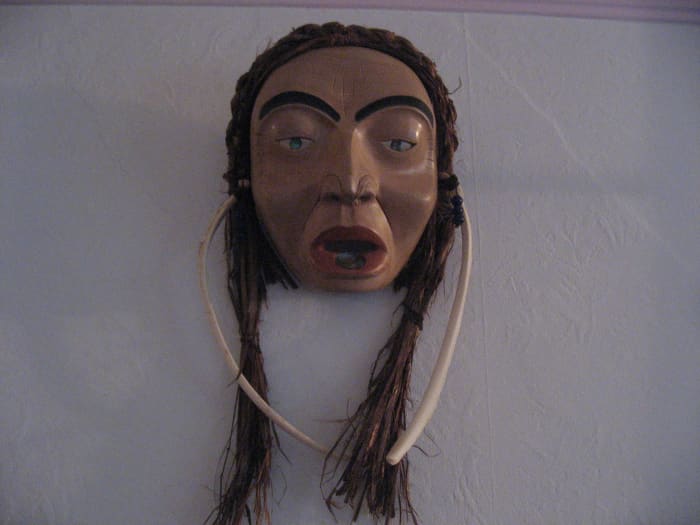 Older woman with labret and bone earrings.This is carved in North West Coast style from Alder with cedar bark hair. it was carved by Marsha Ablowitz