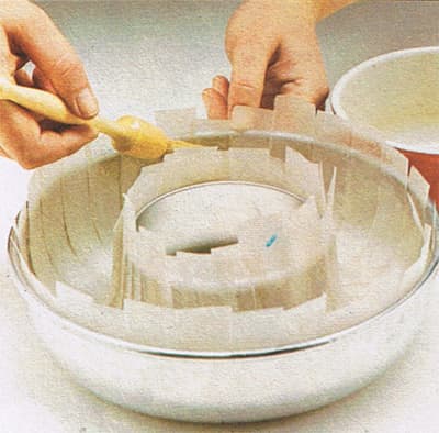 1.Cut 16-20 strips of lining paper, 1 x 7". Grease tin.Push the strips into the tin so that they lie across the tunnel. Overlap strips around inside of tin grease again.