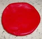 Roll out a ball of red fondant slightly larger than the ball of off-white fondant for the gills and flatten it down into a round.