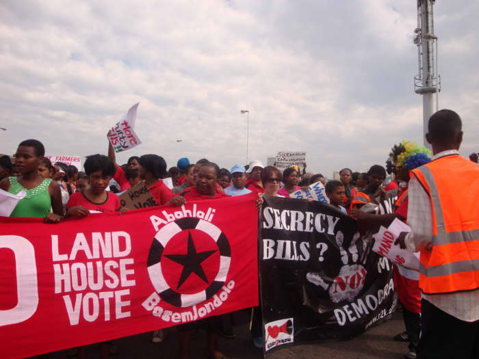 No Land! No House! No Vote" The Banners of the Abahlali baseMjondolo blazon on red and Black and white print as they march to make their case