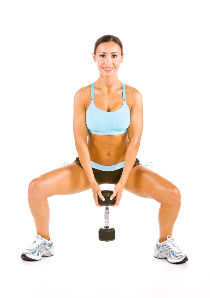 woman exercising with barbell with the wide squat working the interior of the thigh
