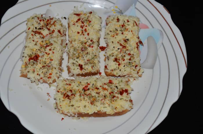 Step two: Spread grated cheese on top of the buttered layer. Sprinkle the mixture of seasonings on the top of each slice.