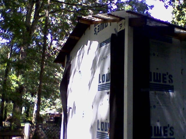 Corners with trim installed over the tar paper. The duct tape has come unstuck on the far corner, causing a sag.