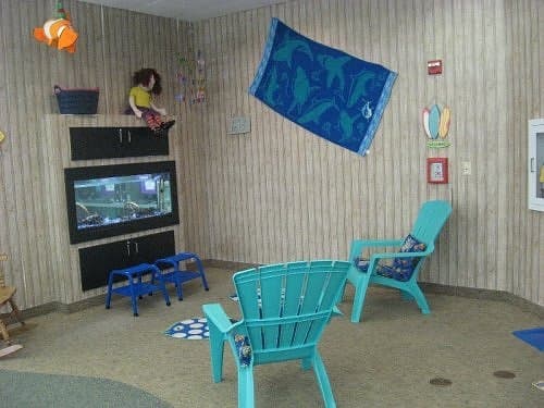 Plastic beach chairs provide seating where a parent can sit to read to a child. The aquarium adds visual interest and serves to divide the children's computer area from the seating area.