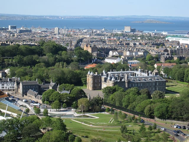 Holyrood Palace, Edinburgh, the official royal residence in Scotland, with the blue waters of the Firth of Forth shining int he distance.