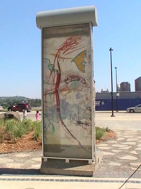 Cincinnati's Berlin Wall Monument stands with the painted side facing the Freedom Center Building. The plain white side faces the Ohio River. Both the river and the Berlin Wall played important roles in the history of freedom.