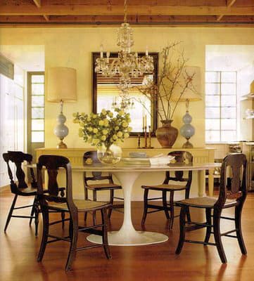 Diningroom of Temple St. Clair Carr, with vintage French lamps and light streaming through industrial steel windows from the kitchen.