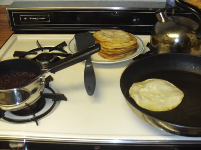 Frying corn tortillas in corn oil and roasting black beans to make tostadas. Yes, these are veggie black bean tacos, which are delicious with tomato, lettuce, and salsa.