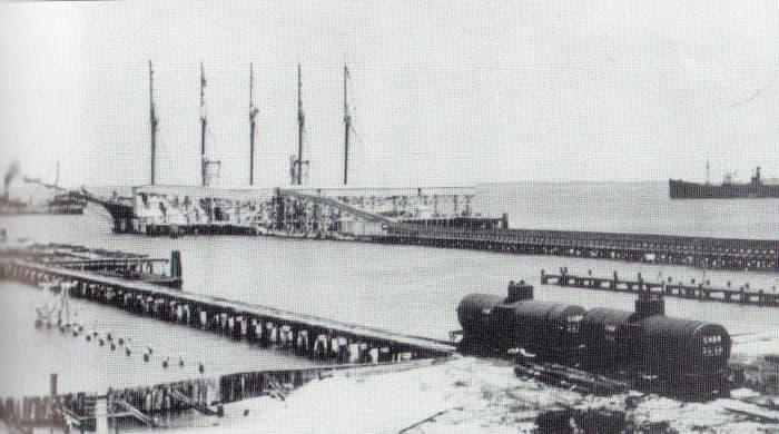 Boca Grande phosphate dock, Circa 1915, is a massive conveyor belt. The phosphate is unloaded at the railhead and carried by the belt to the ship. Note the ship being loaded is a five masted "Yankee Schooner," replaced by steamships by the 1920s.