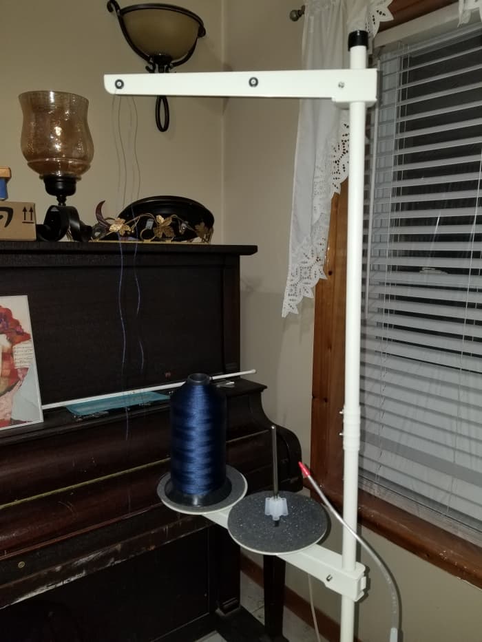 "...lead the thread from the thread stand in the following order." This is the thread stand. Bring your thread upward from the holder and go from back to front through the corresponding hole in the arm.