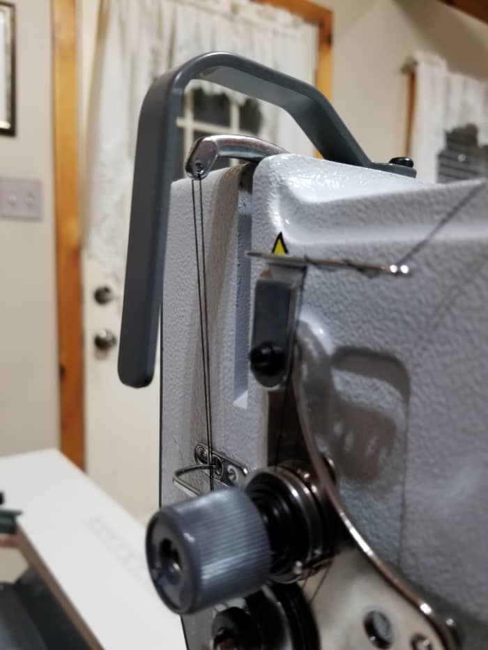 "Raise the needle bar to it's highest point..." The silver piece under the dark gray plastic is the take-up lever. Turn the wheel until this is at its highest point and the needle is as well.