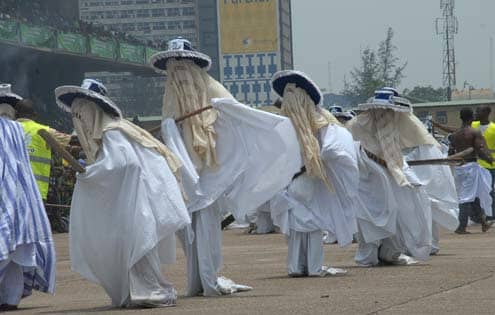 A typical procession of the Eyo masquerades dancing and moving along through the streets of Lagos Island.