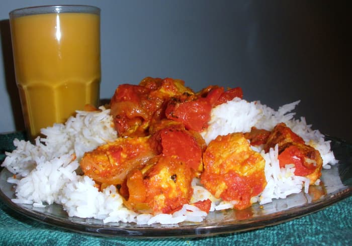 This potluck curry is made with chicken and diced tomatoes. A mango drink made of mango pulp and milk complements the meal.
