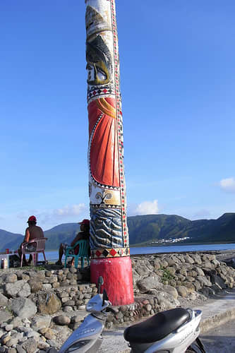 This carved pole appears to be near the shoreline recreation area for tourists. Carved poles were usual in the Eastern Hemisphere before they began appearing in the Pacific Northwest.