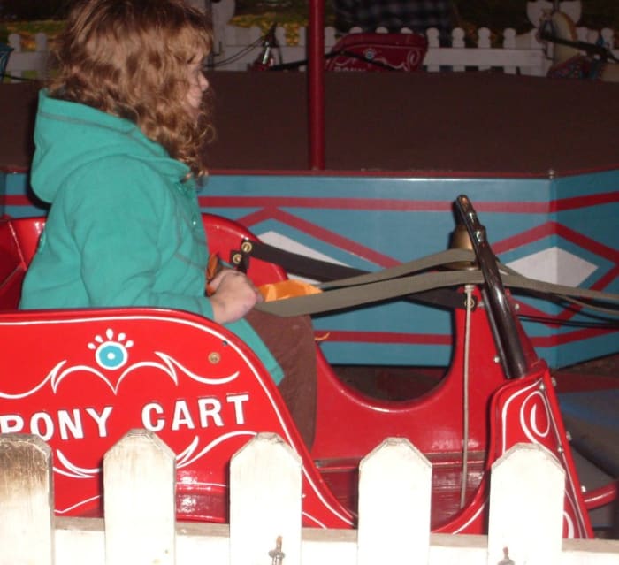 A young girl enjoys the Pony Carts, one of several vintage amusement park rides at Crossroads Village.