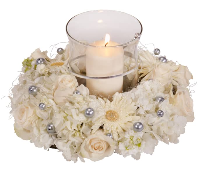 A hurricane vase wih pillar candle, surrounded by a foam ring filled with flowers and accented with oasis mega beads.