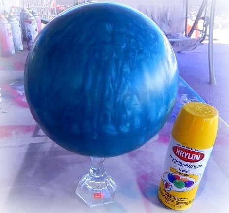 You'll need a cheap bowling ball, a candlestick (or other base), some outdoor spray paint, and other supplies for this project.