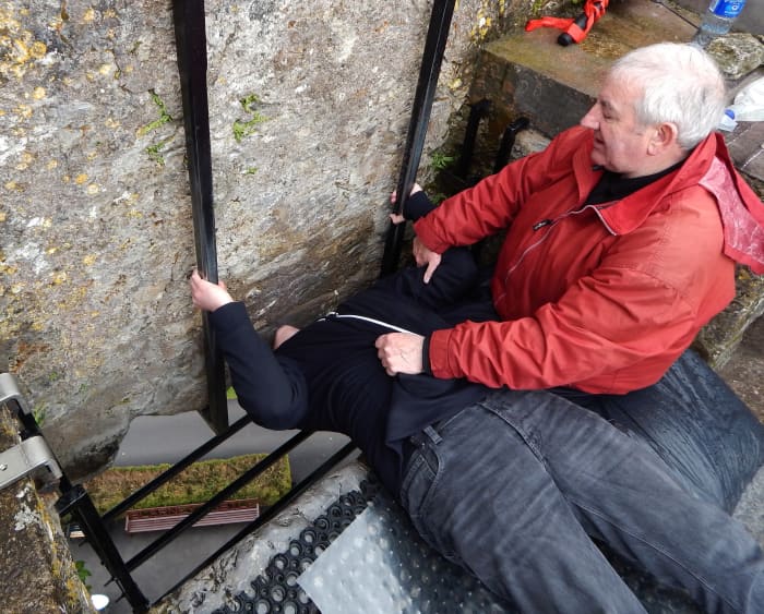 A visitor kissing the Blarney Stone, under the careful supervision of a guide whose job it is to keep adventurers safe.