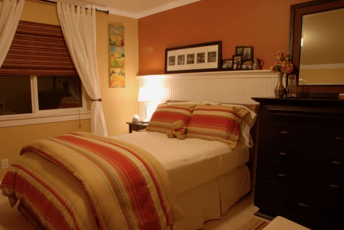 transitional designed bedroom with plate rail / chair rail used in the bedroom to hold photos and mementos in a decorative fashion