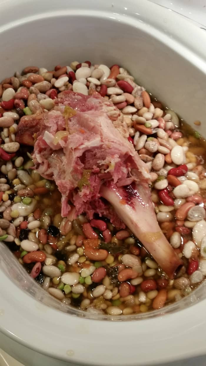 Place the beans and the ham bone in the slow cooker. There are bits of meat and fat clinging to the bone. These will flavor the soup and provide protein.