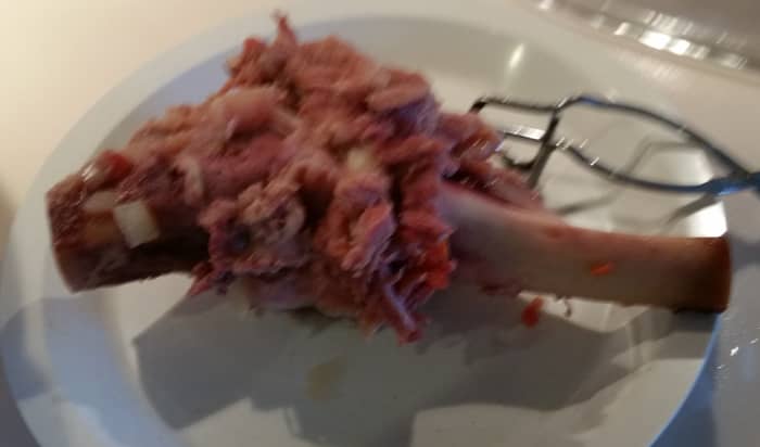 Let it cool, then pull off the bits of meat clinging to the bone. Put the meat back into the soup. Discard the bone.